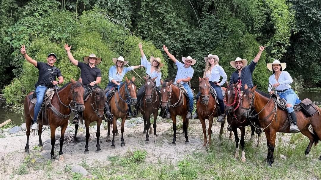 Grupo de cabalgata a caballo a la orilla del río en la reserva