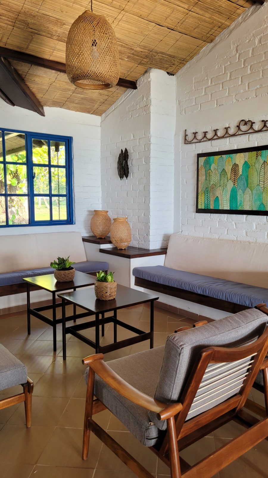 Sala de la casa con ladrillo blanco, ventana azul y lámpara tejida
